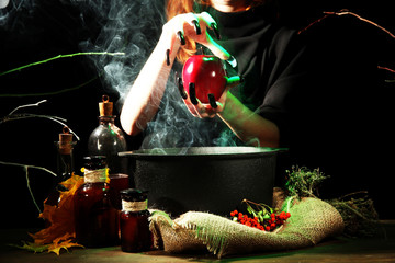 Witch in scary Halloween laboratory on dark color background