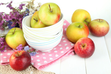 Juicy apples on plate on white wooden table