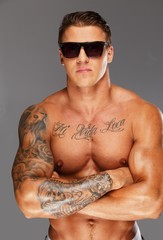 Fototapeta premium Handsome man in sunglasses with muscular tattooed torso