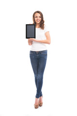 A happy girl in stylish jeans holding a tablet computer