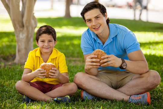 Happy father and son eating burgers