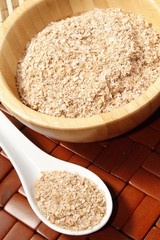 wheat bran in bowl and ceramic spoon