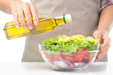 Cook is pouring olive oil into salad