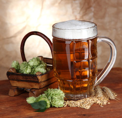 Glass of beer and hops, on wooden table
