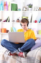 Young man relaxing on sofa with  laptop