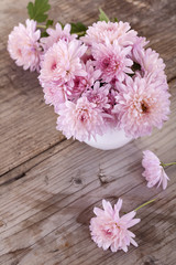 magenta flowers in a white vase on a wooden board