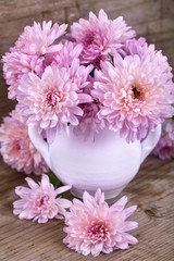 magenta flowers in a white vase on a wooden board