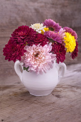 colorful flowers in a white vase on a wooden board