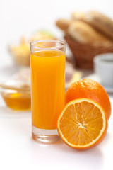 orange juice  with breakfast and coffe in the background