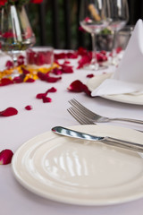 White plate with silverwares set decorated with rose petals