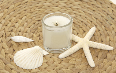 Fototapeta na wymiar seashell with starshell and candle on mat background