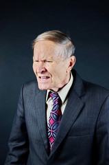 Stressed businessman in suit shouting, man portrait on black background