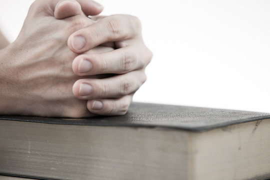 hands praying with bible