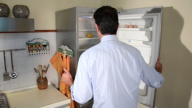 disappointed man looking in his empty fridge