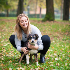 Naklejka na ściany i meble Young woman playing with Australian Shepherd dog outdoors in the