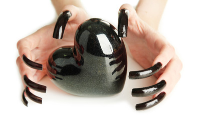 Hands with scary manicure holding black heart , isolated