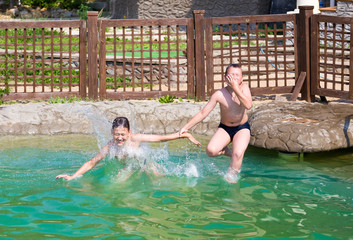 Two boys jump into the pool. Horizontal image