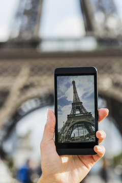 Woman in Paris taking pictures in front of Eiffel Tower, Phone