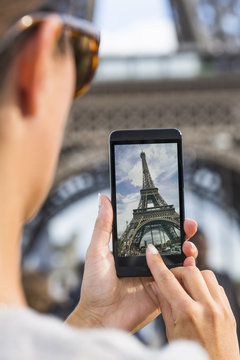 Woman in Paris taking pictures in front of Eiffel Tower
