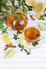 Kettle and cup of tea with ginger on wooden table
