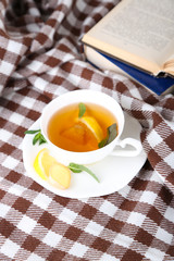 Cup of tea with ginger on plaid with a book