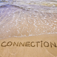 Connection word written on sand, with waves in background