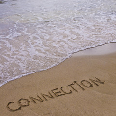 Fototapeta premium Connection word written on sand, with waves in background