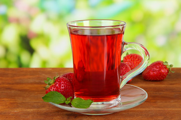 Delicious strawberry tea on table on bright background