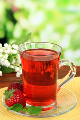 Delicious strawberry tea on table on bright background