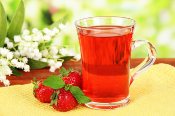 Delicious strawberry tea on table on bright background