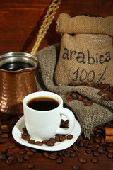 Coffee cup and metal turk on wooden background