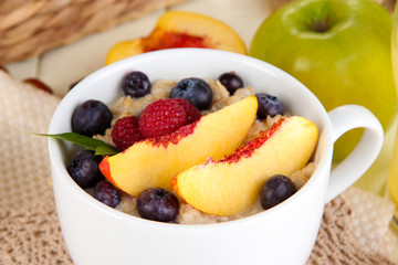 Oatmeal in cup with berries on napkins on wooden table