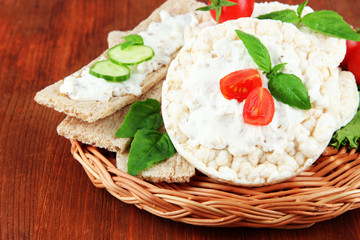 Tasty crispbreads with vegetables on wooden background