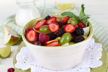 Fruit salad in plates on wooden table near napkin