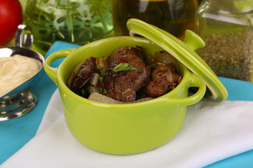 Fried chicken livers in pan on wooden table close-up