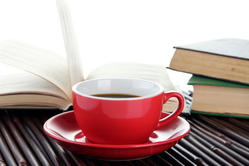 Cup of coffee and books on bamboo mat on white background