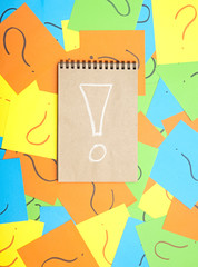 Pile of colorful paper notes with question marks and note book w