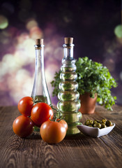 Bottles of olive oil, bunch of tomateos, fresh basil and olives