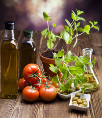 Bottles of olive oil, bunch of tomateos, fresh basil and olives