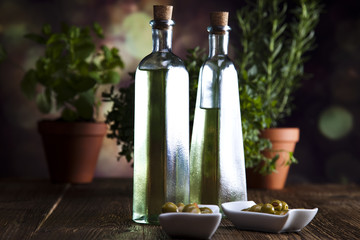 Bottles of olive oil, herbs nad fresh olives on a plate