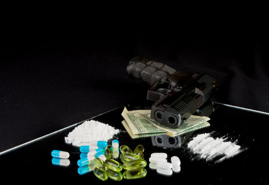 Life is at the edge. Gun, pills, drugs, money on black backgroun