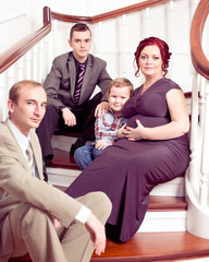 Happy family sitting on the staircase/ Mother is pregnant