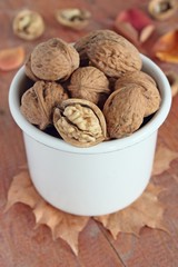 Walnuts in the white bowl on a wooden background