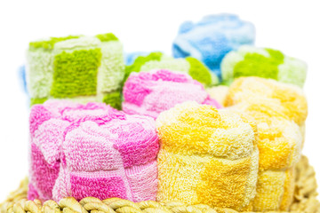 Rolls of different colors of towels in a wicker basket.