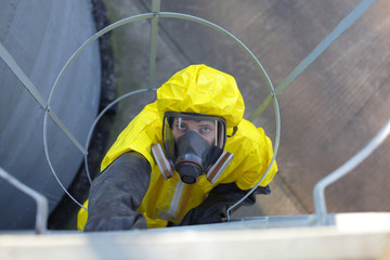 technician in protective uniform going up a metal ladder