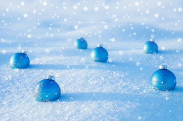 Blue Christmas balls on snow field.