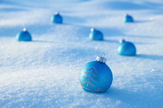 Blue Christmas balls on snow field.