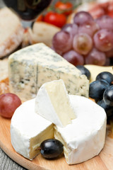 Camembert, blue cheese, grapes and walnuts on wooden board