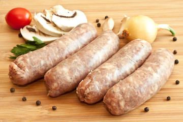 Uncooked sausages with vegetables on the chopping board