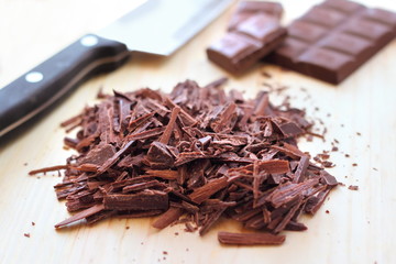 Chopped bar of dark chocolate on wooden background